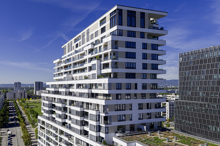 Moderne weiße Wohnanlage mit Balkonen, Beispiel für energieeffiziente Gebäudetechnik und Fassadengestaltung im urbanen Umfeld bei Tageslicht.