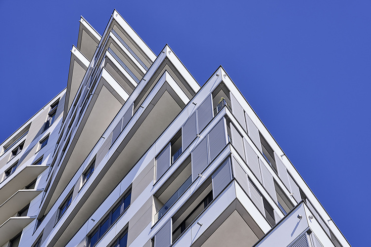 Neubau eines modernen, weißen Mehrfamilienhauses mit markanten Balkonen - Beispiel für energieeffiziente Gebäudehülle in der Gebäudetechnik.
