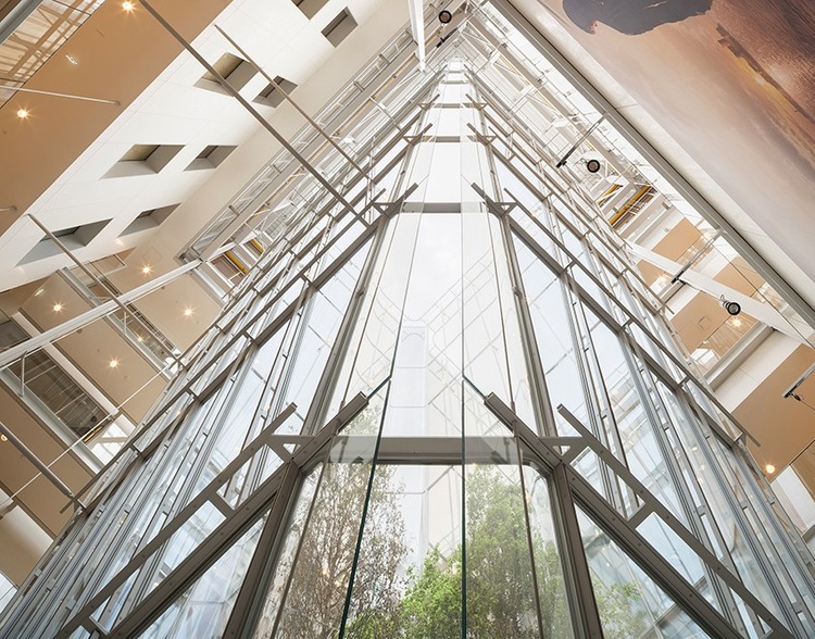 Glasatrium-Decke einer modernen Gewerbeimmobilie, von unten fotografiert; strukturiertes Tragwerk und tageslichtoptimierte Architektur.