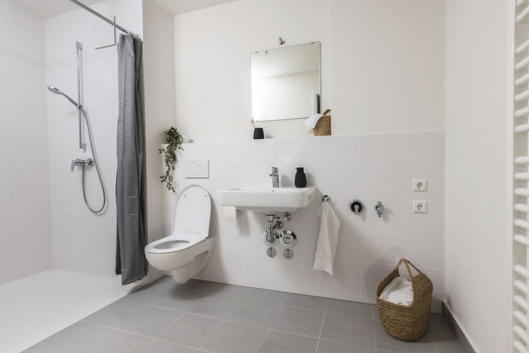 Barrierearmes Bad mit bodengleicher Dusche, wandhängendem WC und Waschtisch - Beispiel für moderne Sanitärtechnik und effiziente Raumnutzung.