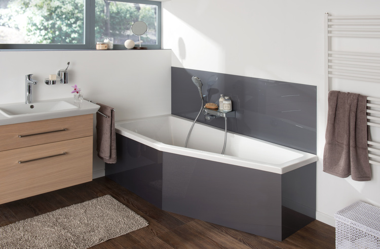 Barrierefreies, modernes Bad mit Eckbadewanne, Waschtisch, Handtüchern und großem Fenster - Tageslichtlösung für energieeffiziente Gebäudeplanung.