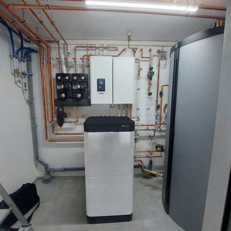 Moderne Heizungsanlage mit Regeltechnik, Rohrleitungen und Pufferspeicher in einem aufgeräumten Technikraum, typische Installation im SHK-Bereich.