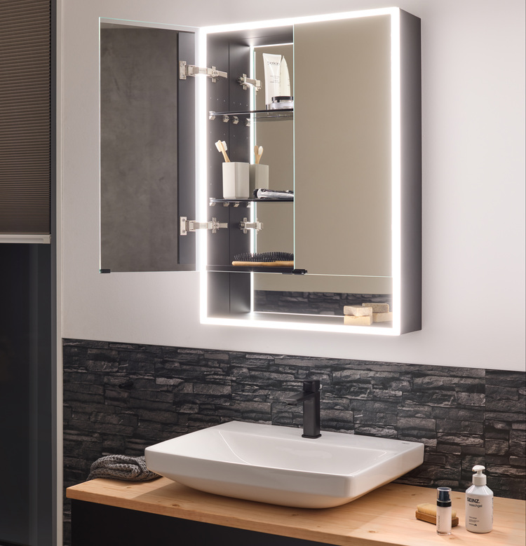 Beleuchteter Spiegelschrank in einem modernen Bad, geöffnet, zeigt strukturierte Ablagefächer über Waschtisch und Armatur für effiziente Badorganisation.