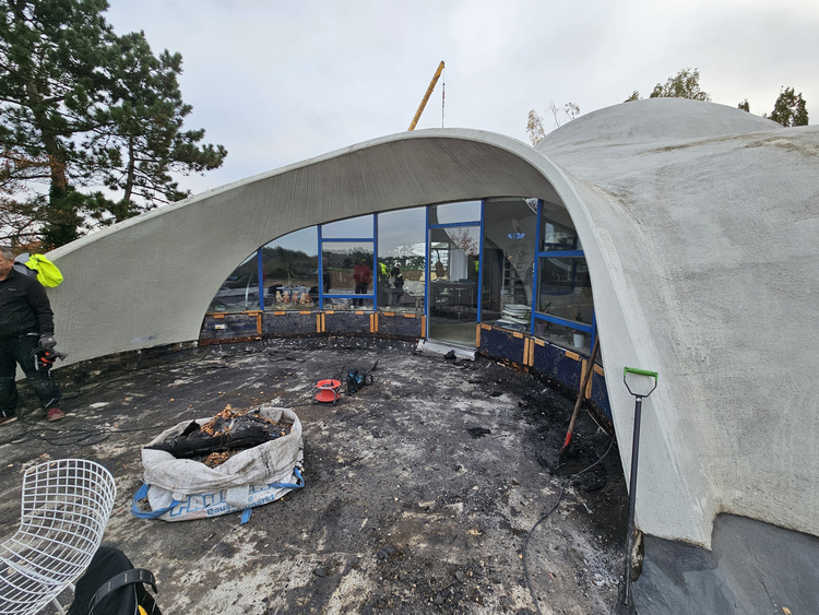 Im Bau befindliches Kuppelgebäude aus Beton mit gewölbtem Eingangsbereich und vorgelagertem Außenbereich, geeignet für moderne Gebäudetechnik.