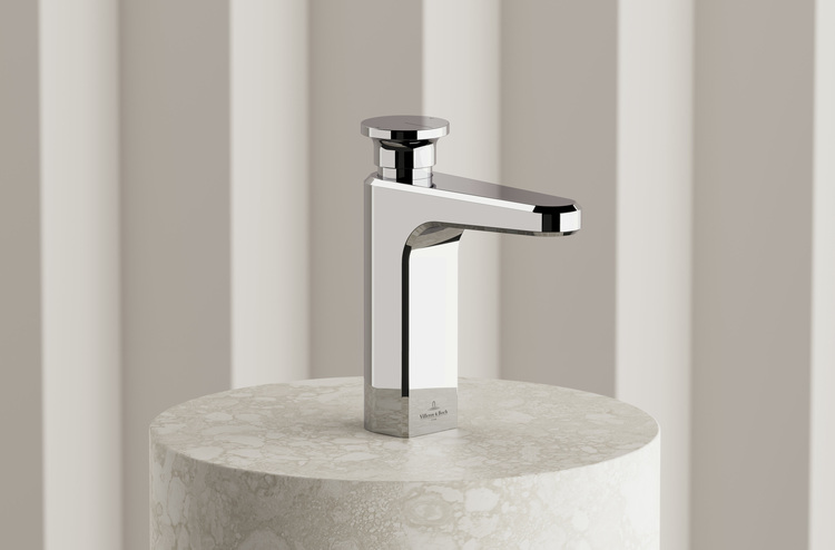 Zeitgemäße verchromte Waschtischarmatur auf rundem Marmor-Sockel, inszeniert vor neutralem gestreiftem Hintergrund für Sanitärtechnik-Bereich.