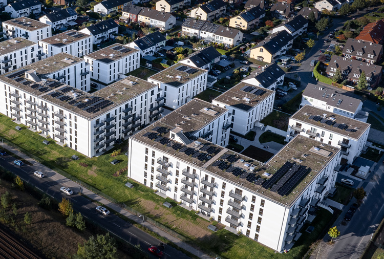 Luftaufnahme moderner Mehrfamilienhäuser mit Photovoltaikanlagen auf den Dächern, Beispiel für energieeffiziente Gebäudetechnik in einem Wohnviertel.