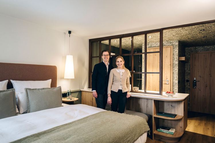 Zwei Fachleute im Hotelzimmer prüfen energieeffiziente Gebäudetechnik; Fokus auf moderne Raumgestaltung und nachhaltige Lösungen.