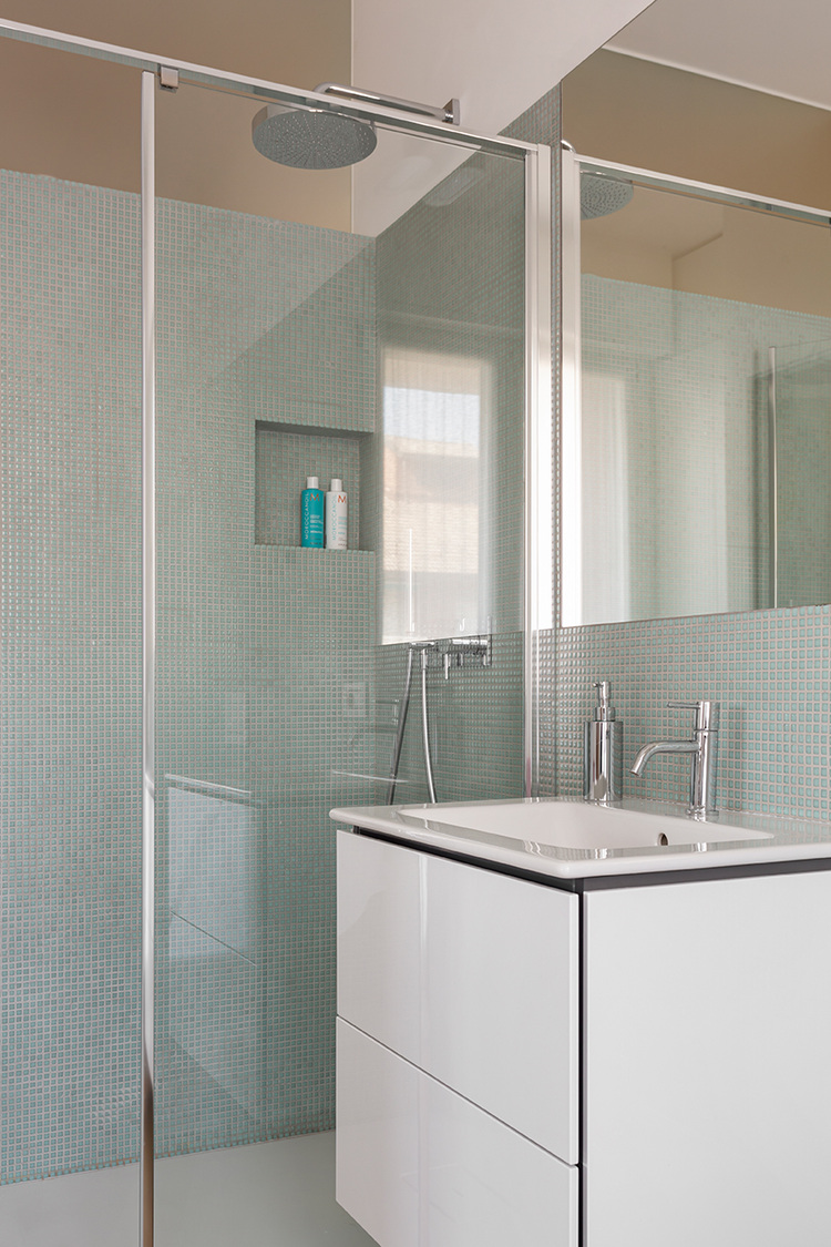 Barrierefreies Bad mit Echtglas-Dusche, wandbündigem Regen-Duschkopf und weißem Waschtischunterschrank - Beispiel für moderne Sanitärtechnik.