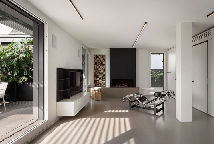 Modernes Wohnzimmer mit effizientem Gaskamin, wandmontiertem TV und großer Fensterfront für optimale Tageslichtnutzung und Energieeinsparung.