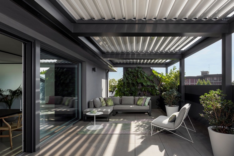 Moderne Terrasse mit Lounge-Mobiliar, Begrünung und Pergola mit Lamellendach zur Tageslichtsteuerung - Beispiel für innovative Gebäudetechnik-Lösungen.