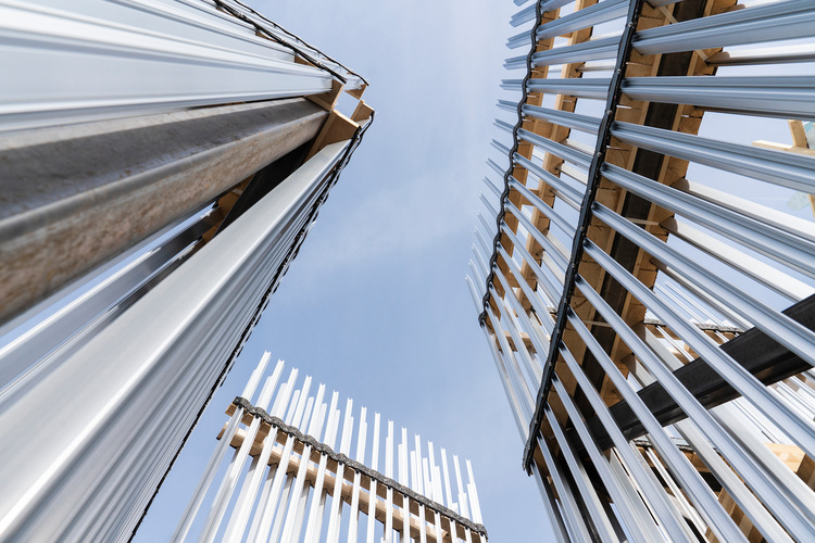 Vertikal angeordnete Metallträger und Stützen, fotografiert von unten vor blauem Himmel - Beispiel für moderne Gebäudetechnik im Stahlbau.