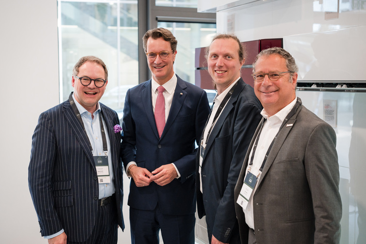 Vier Fachbesucher aus der Gebäudetechnikbranche in Businesskleidung auf einem Branchenevent, Netzwerken bei einer Fachmesse für SHK und TGA.