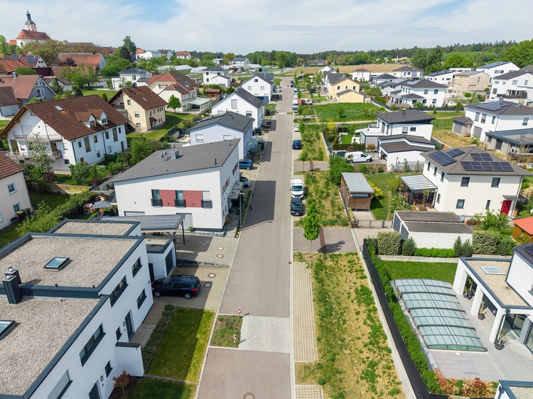 Luftaufnahme eines Wohngebiets mit modernen Häusern, energieeffizienter Gebäudetechnik und begrünten Freiflächen, relevant für Entscheidungsträger im Bereich Gebäudetechnik.