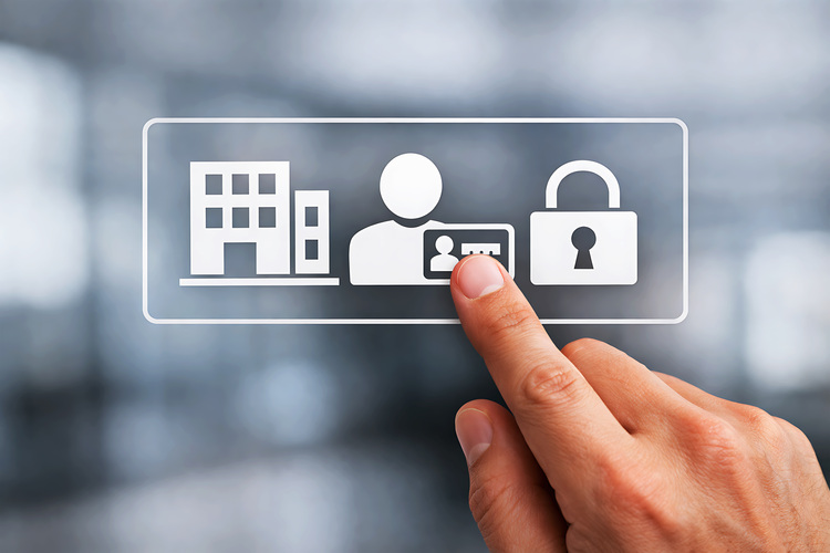 Eine Hand berührt auf einem transparenten Bildschirm Symbole für Gebäude, Nutzer, Zugangskontrolle und Sicherheit – Themen der Gebäudetechnik.
