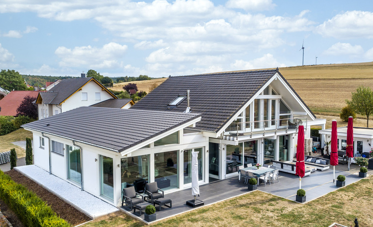 Modernes Einfamilienhaus mit großen Fenstern, energieeffizienter Gebäudehülle und Terrasse in ländlicher Umgebung – ein Beispiel für moderne Gebäudetechnik.