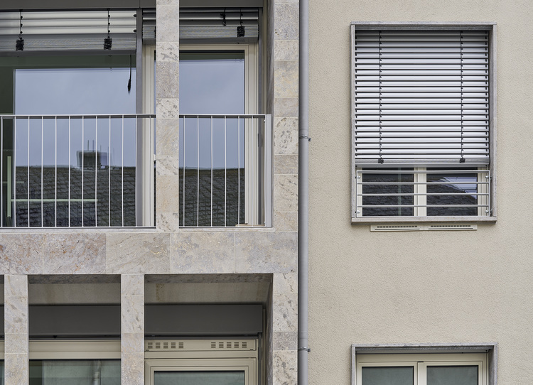 Fassade eines modernen Bürogebäudes mit großflächigen Wärmeschutzglasfenstern, Metallgeländern und gedämmten Fassadenelementen für Energieeffizienz.