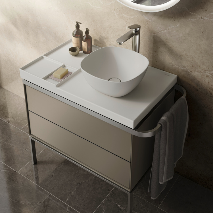 Waschtisch mit Aufsatzwaschbecken, Armatur, Seifenspender und Handtuch vor einer Marmorwand – Beispiel für eine moderne Sanitärinstallation.