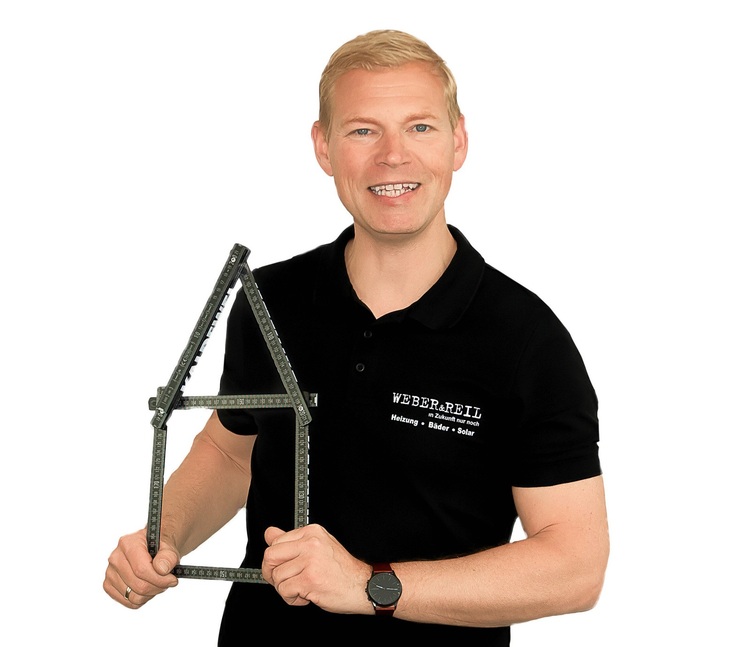 Ein Fachmann in einem schwarzen Polo-Shirt hält vor weißem Hintergrund ein hausförmiges Messinstrument in der Hand, das als Symbol für Gebäudetechnik-Lösungen steht.