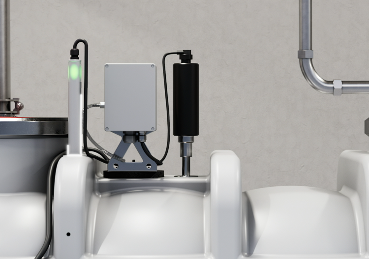 Detailansicht einer Gebäudetechnik-Steuerung mit Kabeln, Rohrleitungen und einer grünen Betriebsanzeige vor einer grauen Wand.