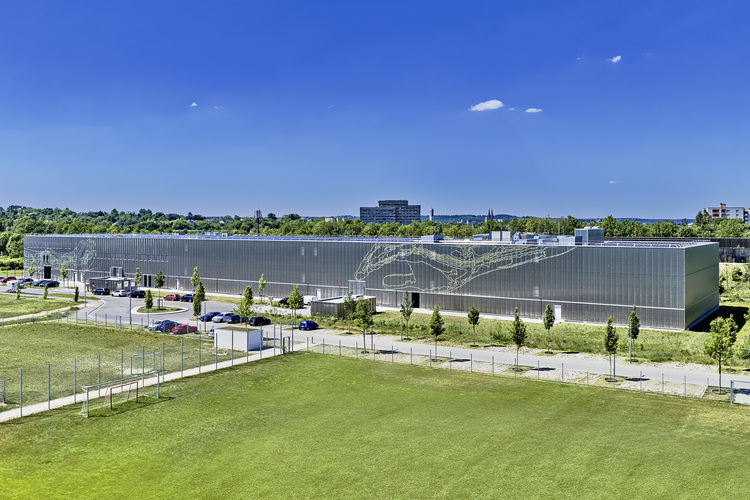 Neubau eines Kompetenzzentrums für Gebäudetechnik mit moderner Metallfassade, rechteckig, an einer Grünfläche gelegen, geeignet für die SHK-Branche und TGA-Experten.