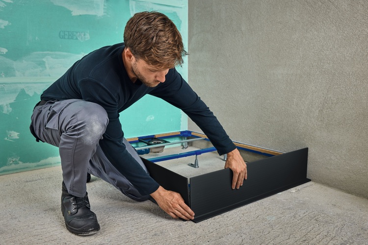 Ein Fachhandwerker bringt eine schwarze Dämmplatte an einer Wand im Rohbau an, um eine optimale Energieeffizienz im Gebäude zu gewährleisten.