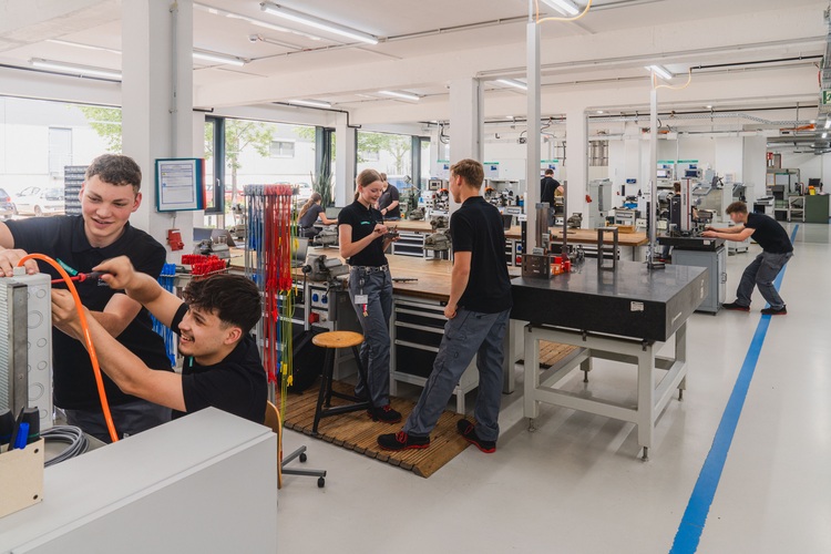Fachkräfte aus dem Bereich Gebäudetechnik arbeiten gemeinsam in einer modernen, hellen Werkstatt an Anlagen für Heizung, Sanitär und Klimatechnik.