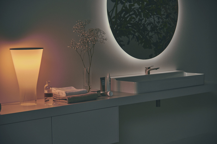 Barrierefreies, modernes Badezimmer mit beleuchtetem Rundspiegel, Aufsatzwaschbecken, Handtüchern und energiesparender LED-Leuchte für die Gebäudetechnik.