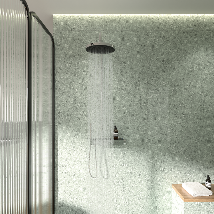 Barrierefreies Badezimmer: bodengleiche Regendusche, grüne Terrazzo-Wand, Holzablage mit Handtüchern und Pflegeprodukten.