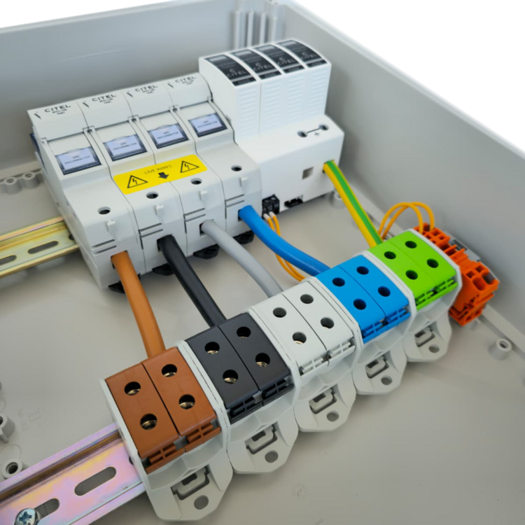 Detailansicht eines Installationskastens mit farbigen Kabeln an beschrifteten Klemmen und Sicherungsautomaten in einer Gebäudetechnik-Anlage.