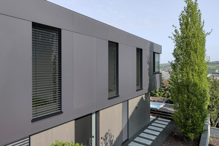 Zweistöckiges, modernes Gebäude mit großen Fenstern und geschlossenen Jalousien, geeignet für energieeffiziente Gebäudetechnik.