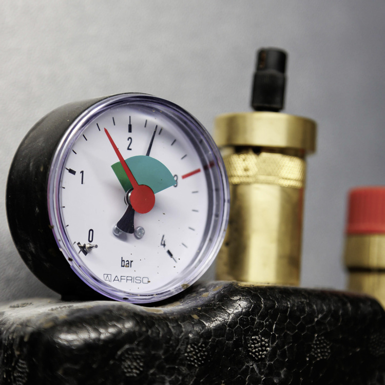 Manometer mit Anzeige bei ca. 2,2 bar, Messingverschraubungen und rotem Sicherheitsventil – ein typisches Detail in der Gebäudetechnik.
