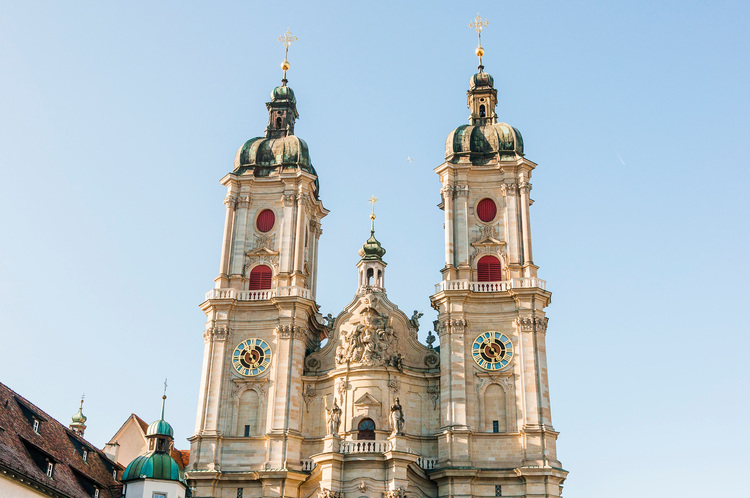 Barocke Kathedrale mit zwei Türmen, Uhren und roten Fensterrahmen, Beispiel für eine historische Gebäudehülle und Energieeffizienz.