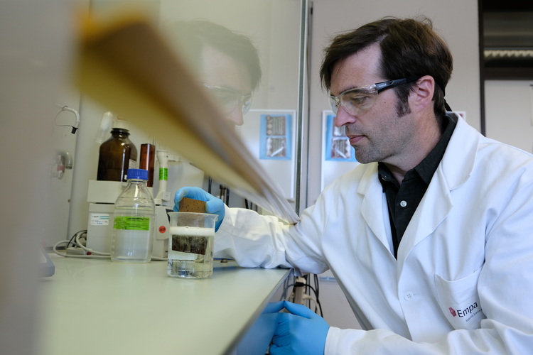 Eine Fachkraft untersucht Flüssigkeiten im Labor für Gebäudetechnik, wobei der Schwerpunkt auf innovativen Lösungen in den Bereichen Heizung, Lüftung und Sanitär liegt.
