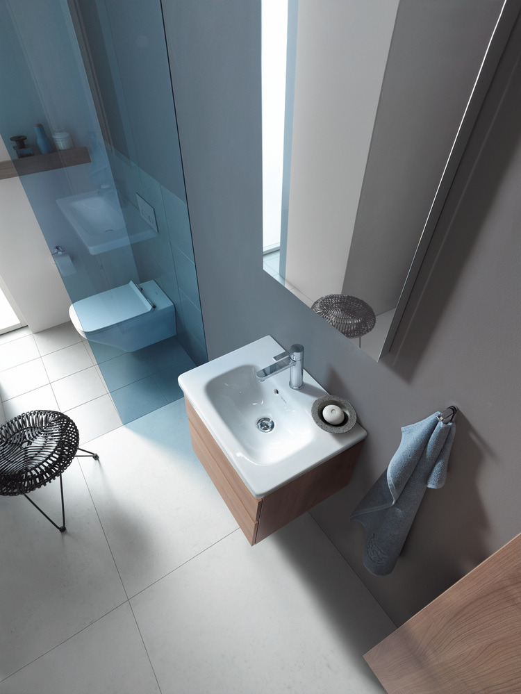 Barrierefreier Sanitärraum mit wandhängendem Waschbecken, WC und Duschbereich mit blauen Fliesen; geeignet für moderne Gebäudetechnik.