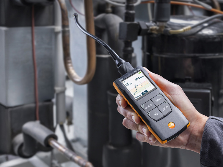 Ein Fachmann misst mit einem digitalen Gasanalysegerät mit Display die Emissionen direkt an der gebäudetechnischen Anlage, um deren Effizienz zu überprüfen.