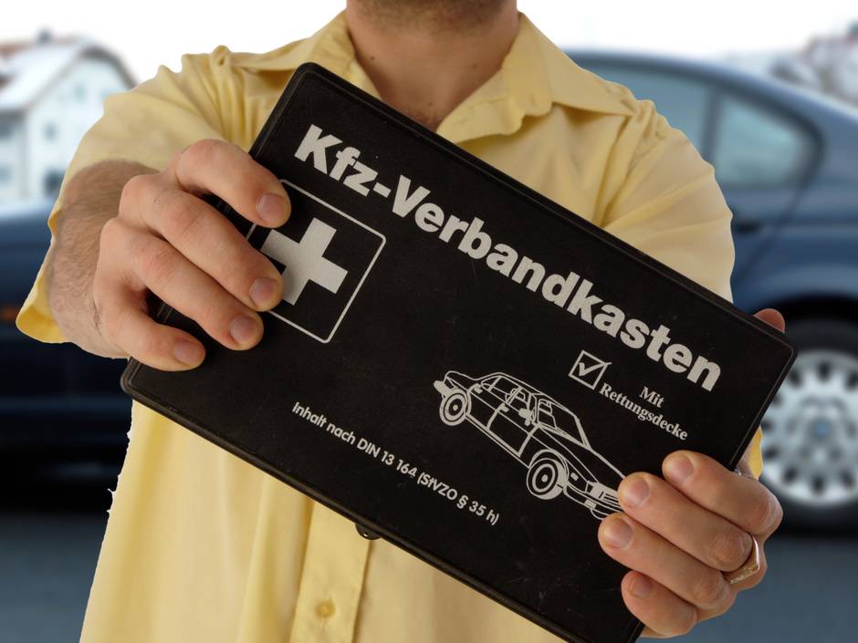 Mann hält einen Kfz-Verbandskasten.