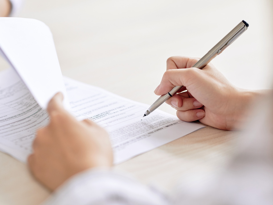 Stift in der Hand mit einem Vertrag