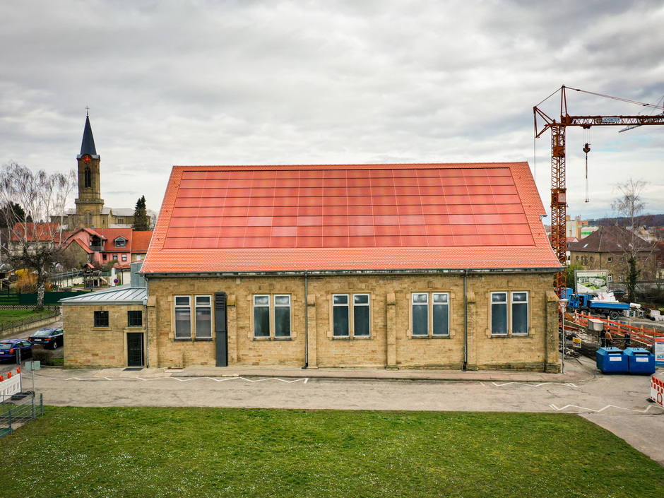 Historisches Gebäude in Eppingen mit einer roten, ins Dach integrierten Photovoltaik-Anlage. Eine homogene Integration von Photovoltaik steigert deren Akzeptanz.