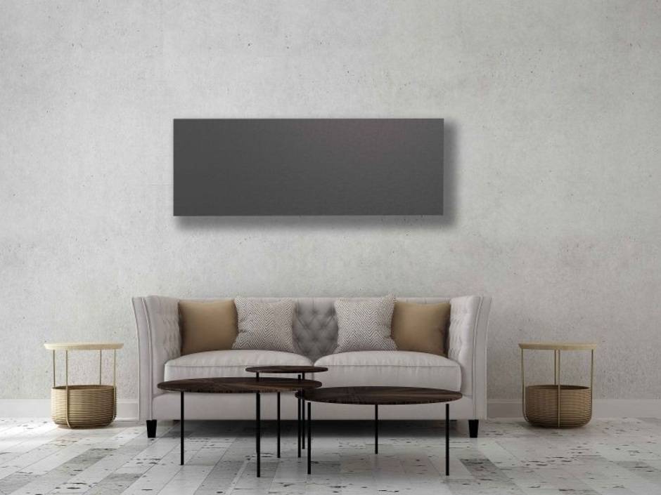 Infrarotheizung an einer Waschbetonwand über einem Sofa.