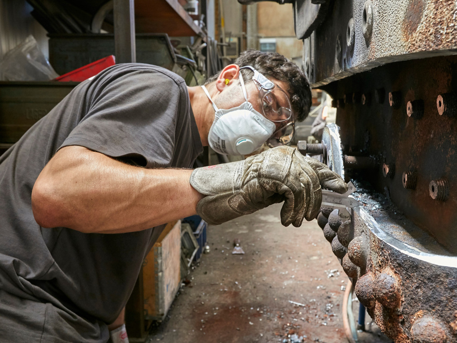 Ein Mann restauriert einen Metallgegenstand.