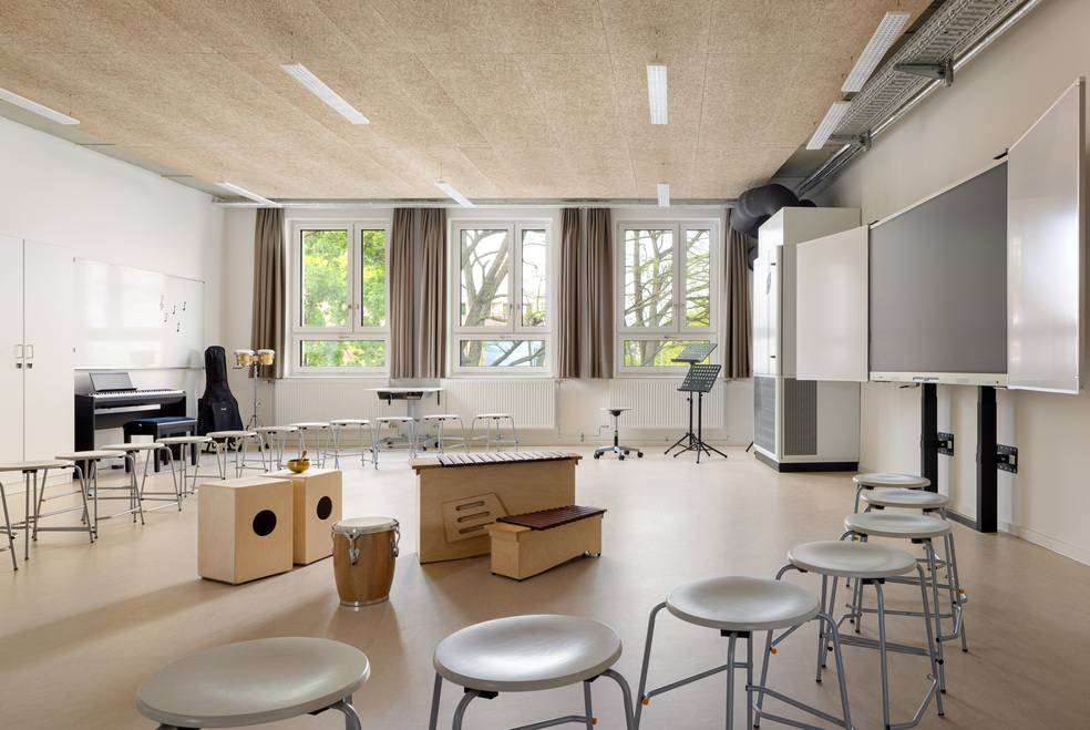 ALT-Text: „Modernes Schulungszimmer für Gebäudetechnik mit ergonomischen Sitzgelegenheiten, energiesparender Lüftungsanlage, interaktivem Whiteboard und großen Fenstern zur Optimierung des natürlichen Lichteinfalls.