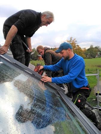 Lutz Wittenbecher (links) und Eugen Wedel (Mitte) von der Dachdeckerei George sowie Daniel Lüdeke von LiDEKO montieren den Eindeckrahmen.