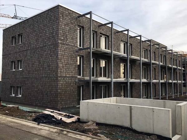 Das Bauprojekt weist eine positive CO2-Bilanz auf. Die Holzschindeln geben den beiden Gebäuden einen außergewöhnlichen Look.  Das Bauprojekt weist eine positive CO2-Bilanz auf. Die Holzschindeln geben den beiden Gebäuden einen außergewöhnlichen Look.