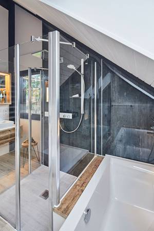 Die Duschkabine grenzt direkt an die Badewanne, dadurch wurde der Raum optimal ausgenutzt und auch die Dachschräge perfekt mit integriert. Die auf Maß gefertigte Seitenwand hat eine exakt auf den Badewannensockel abgestimmte Höhe.