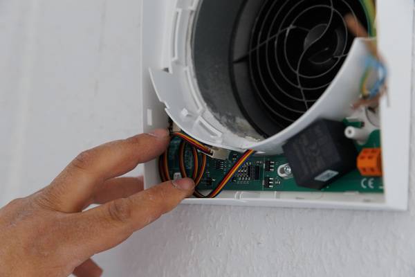 Alt-Text-Vorschlag: "Fachhandwerker installiert Steuerungselektronik für eine moderne Heizungsanlage an einer Wand - Detailaufnahme der Verkabelung und Klemmen, Fokus auf Gebäudetechnikinstallation.