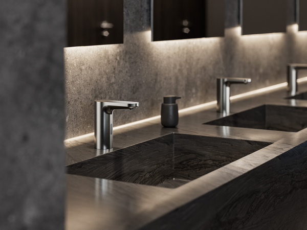 Waschtischanlage mit modernen Armaturen, Seifenspender und LED-beleuchteter Steinplatte vor einer grauen Wand im Sanitärtechnik-Showroom.