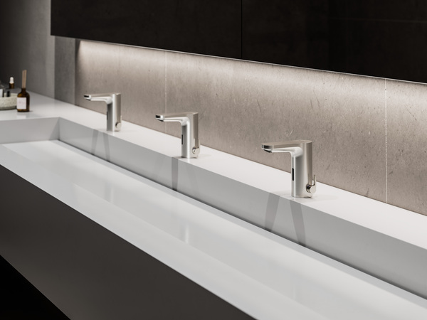 Barrierefreie Sanitäranlagen: Drei berührungslose Waschtische mit Sensorarmaturen, graue Steinrückwand, moderne Gebäudetechnik.