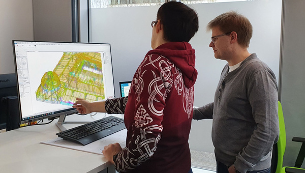 Zwei Mitarbeitende von einem Bildschirm mit CAD-Software