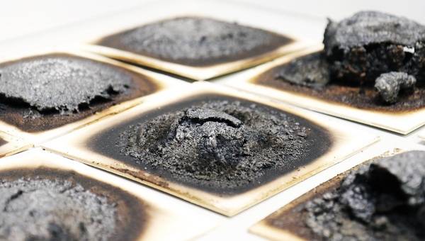 Verschiedene intumeszierende Beschichtungen nach der Beflammung im Laborbrandprüfstand des Fraunhofer WKI. Die Tests geben Aufschluss darüber, mit welcher Rezeptur sich das darunterliegende Holz am besten schützen lässt.