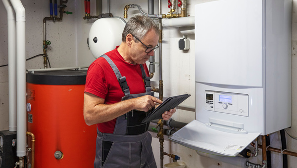 Mann mit Tablet im Heizungskeller